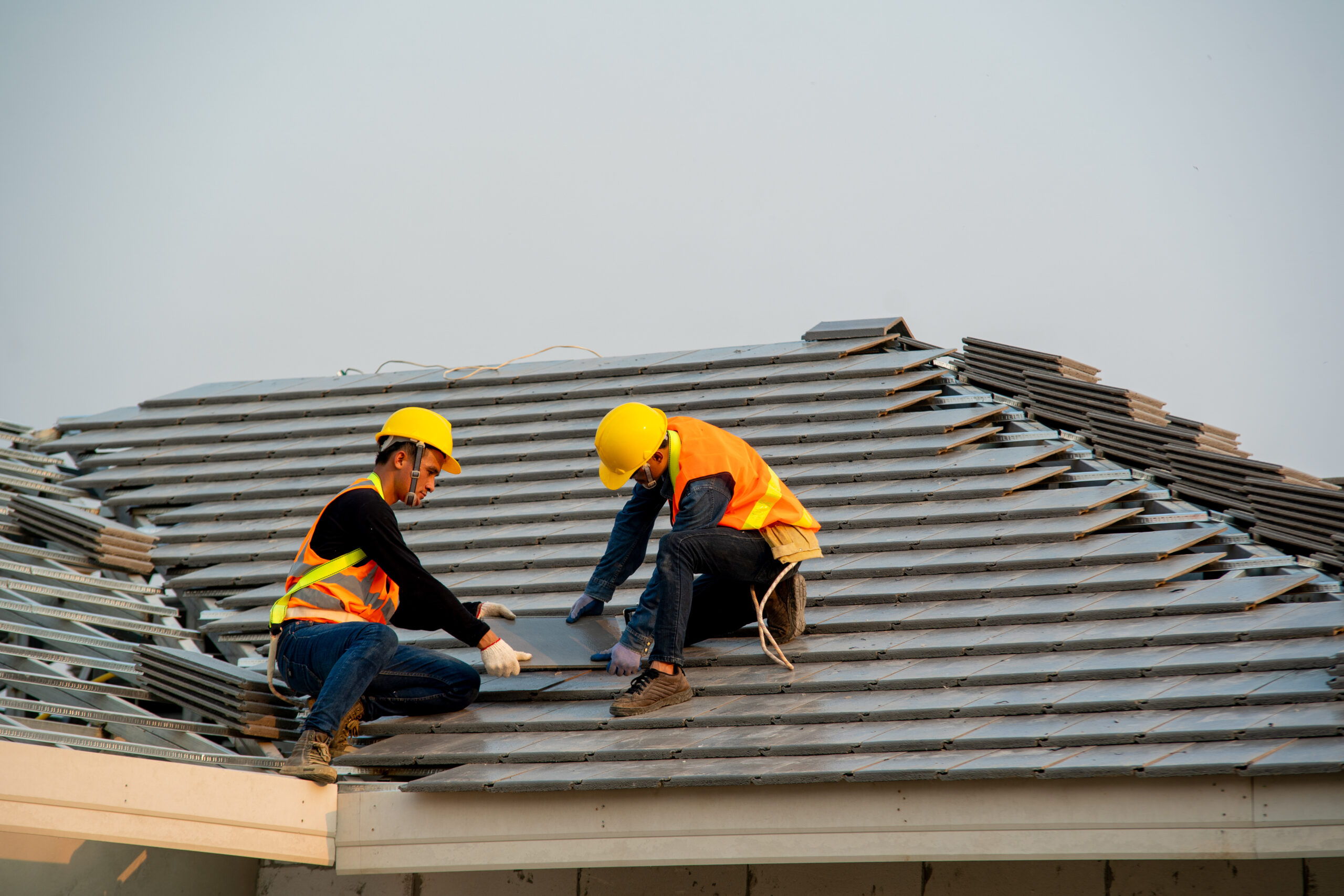 Roofer working on roof structure are installing new roof,Two roofers inspecting new roof. Roofer working on residential roof preparation in Florida before hurricane season – All Phase Roofing